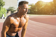© Addoro - Handsome middle aged man warming up on a running track. Healthy adult man preparing for a run on the track. Tanned skin and shirtless middle-aged man.