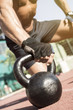 © Addoro - Close up shot of a man's hand on a kettlebell. Crossfit instructor at the track.
