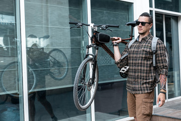 Poster - Handsome Young Man With Glasses Carries Bicycle On His Shoulder Lifestyle Daily Routine Concept