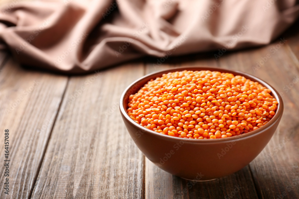 Bowl of red lentils on wooden background