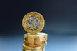 The new one pound coin balancing on it's edge on top of a pile.