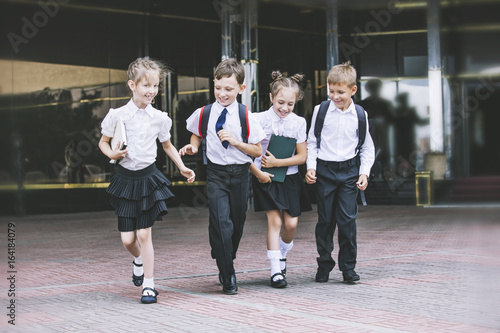 Plakat Piękne dzieci w wieku szkolnym aktywne i szczęśliwe na tle szkoły w mundurze