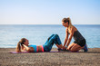 Coaching sportif face à la mer: jeune femme faisant des exercices d'abdominaux avec son coach.
