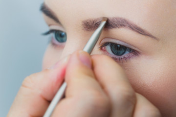 Woman with blue eyes getting makeup on brows