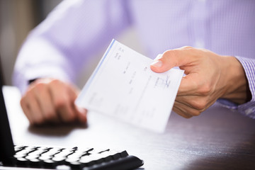 Businessperson's Hand Holding Cheque