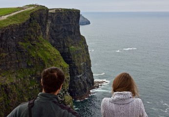 young couple at cliffs of moher - a young couple touring in ireland view the cliffs of moher during 