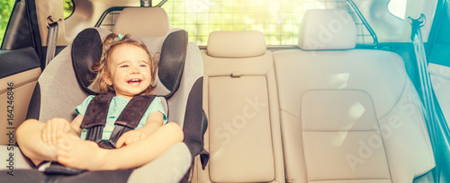 Fototapeta Infant baby girl buckled into her car seat.