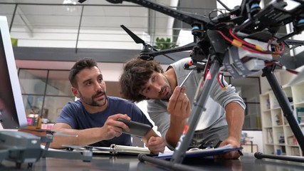 Engineer and technician working together on drone in office