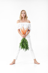 Sticker - Beautiful blond woman  holding fresh carrot with green leaves on white background. Health and Diet