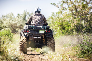 Back view of quad bike  riding along a country road.