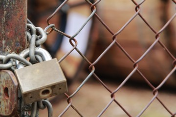 The metal mesh gate is closed and locked with a key. See inside