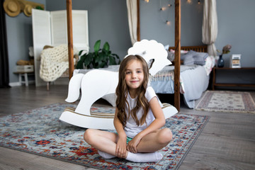 Wall Mural - Cute little girl riding a toy horse