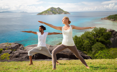 Canvas Print - couple making yoga in warrior pose at seaside