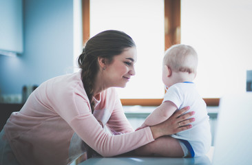 Mother with her baby in the bright kitchen at home.