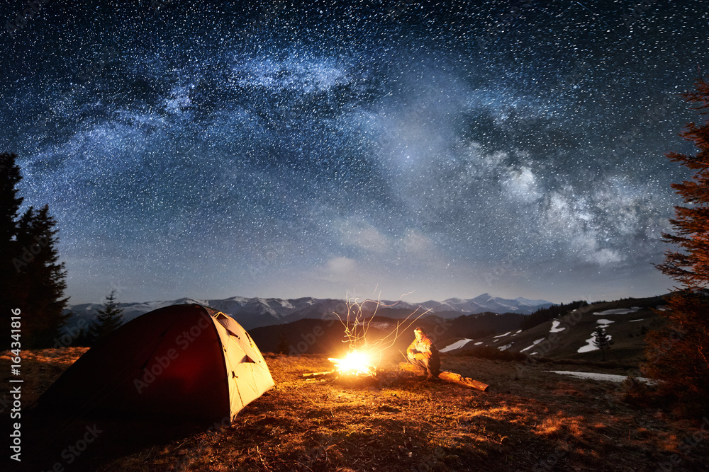 Male tourist have a rest in his camp near the forest at night. Man ...