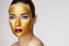 Golden Face Mask. Beautiful Girl With Gold Mask On Facial Skin