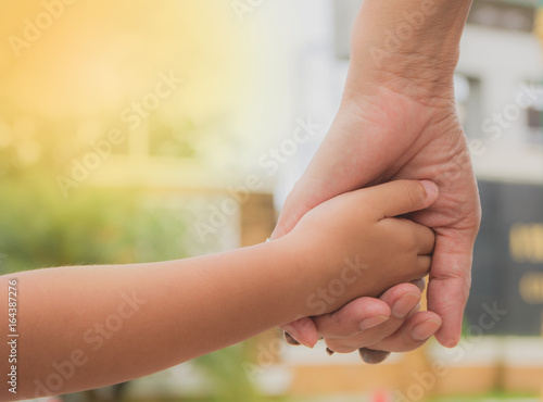 Plakat Zakończenie matka i dziecko up wręcza przy zmierzchem. Macierzysty mienie ręka syn w letnim dniu outdoors.
