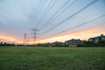 Wall Mural - Group silhouette transmission towers (steel lattice/power tower, electricity pylon) next to apartment complex at sunset in US. Texture high voltage pillar, overhead power line, industrial background.