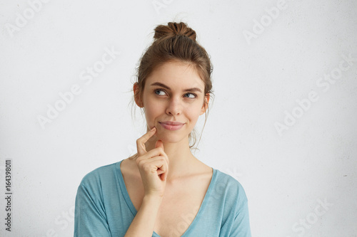 Fotografía Dreamy young woman looking thoughtfully aside holding her finger on chin dreaming about honey moon with her future husband