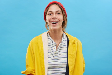 Wall Mural - Cheerful teenage girl wearing trendy colorful clothing rejoicing at positive news, looking at camera with charming smile, showing her perfect white teeth. People, lifestyle, youth and happiness