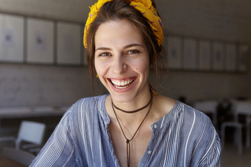 Portrait of positive female student dressed casually sitting in classroom smiling gently having cheerful expression. Happy beautiful female rejoicing her success with studying. Happiness concept