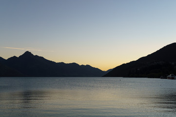 Sunset silhouette mountains, lake in foreground