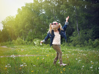 happy little girl dancing in the field. child with a bouquet of flowers. beautiful, sun rays