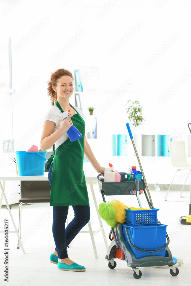 Cleaning service concept. Young woman with bottle of detergent in office