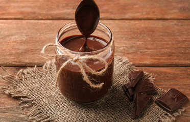 Sticker - Jar with delicious chocolate sauce on wooden background