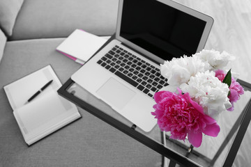 Wall Mural - Bouquet of beautiful peonies and laptop on glass table in room