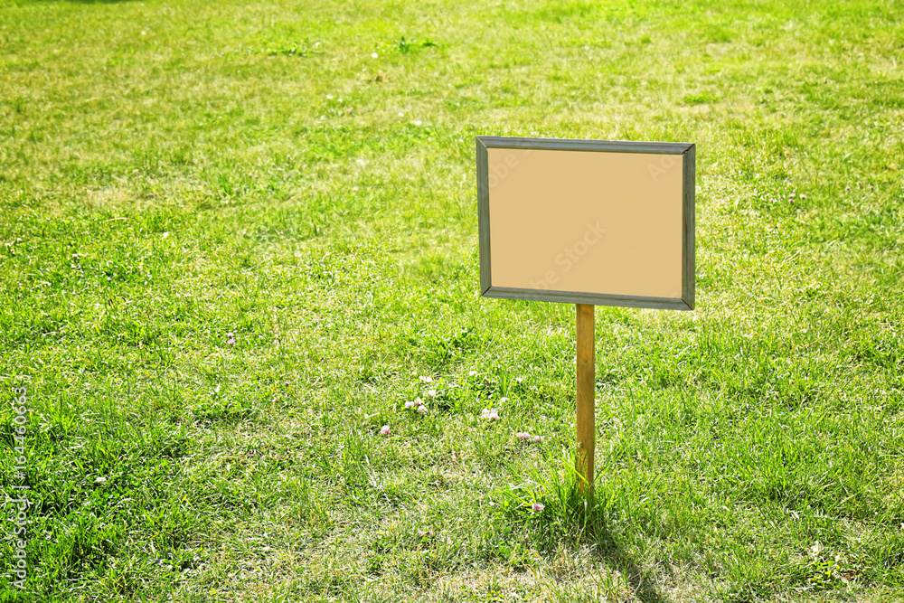 Blank board on green lawn in park