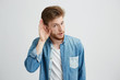 © Cookie Studio - Portrait of young handsome man eavesdroping looking at camera over white background.