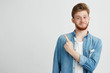 © Cookie Studio - Portrait of cheerful young handsome guy smiling looking at camera pointing finger up over white background.