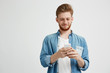 © Cookie Studio - Happy young handsome man smiling looking at phone surfing internet browsing web over white background.