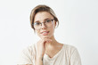 © Cookie Studio - Young tender pretty girl in glasses smiling looking at camera holding hand on chin over white background.