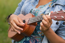 Young Hipster Woman Playing On Ukulele Outdoors