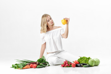 Sticker - Beautiful blond woman in white clothes and lots of fresh vegetables on white background. Girl holds bell pepper