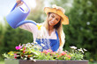 © Kalim - Woman watering plants outside in summer