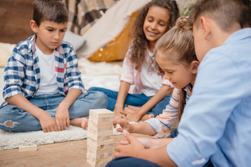 multicultural group of children playing blocks wood game together at home