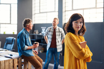 Wall Mural - Focused young businesswoman with colleagues in the background