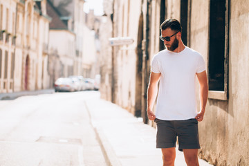 Hipster handsome male model with beard  wearing white blank  t-shirt with space for your logo or design in casual urban style