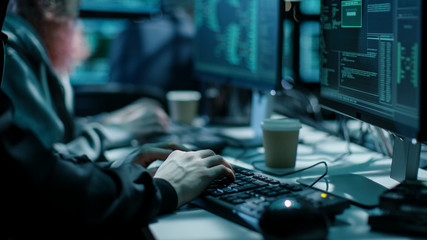 Aufkleber - Close-up Shot of Hacker using Keyboard. There is Coffee Cups and Computer Monitors with Various Information.