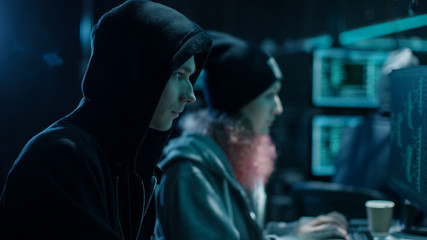 Aufkleber - Close-up Shot of Internationally Wanted Boy and Girl Hackers Team Working on Their Computers. Place is Hacker's Den with Dark atmosphere.