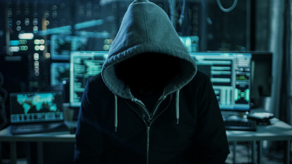 Aufkleber - Dangerous Internationally Wanted Hacker Wth Hided Face Looking into the Camera. In the Background His Dark Operating Room with Multiple Displays and Cables.