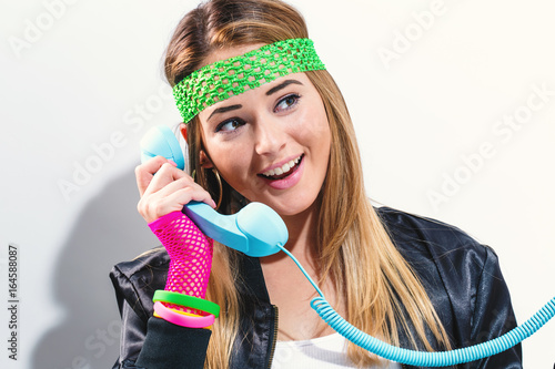 Woman in 1980's fashion with old fashioned phone on a white background