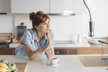 Pretty Ginger Caucasian Woman Standing At Kitchen And Enjoying Morning Coffee.
