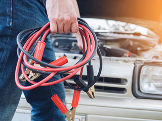 Hand holding jumper cable car battery