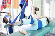 Rehabilitacja, ćwiczenia poprawiające sprawność nogi. Pacjent ćwiczy na podwieszkach w klinice rehabilitacyjnej.