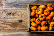 Box of fresh fruits persimmon kaki on wooden background. Copy space