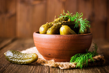 Wall Mural - Pickled cucumbers with dill in ceramic bowl on dark rustic wooden table.